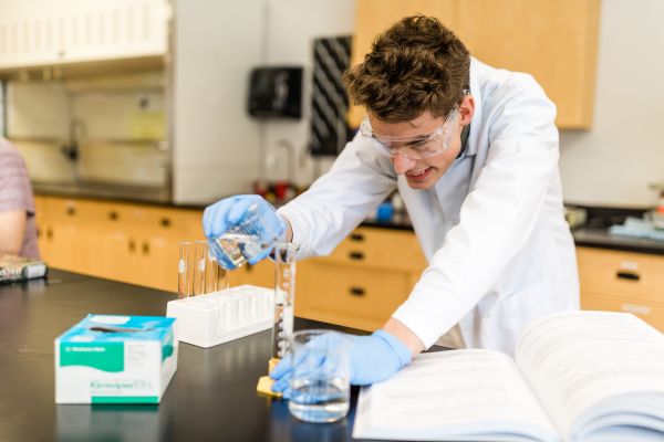 Science student overlooking a beaker conducting an experiment