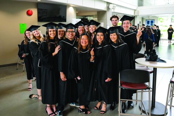 A group of students in cap and gown celebrating graduation.