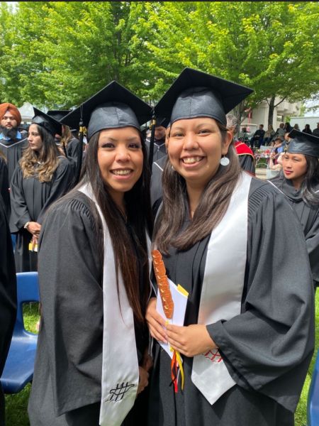 Two students at a convocation ceremony wearing Indigenous stoles